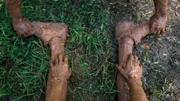 Seorang peserta membantu meregangkan kaki rekannya saat mengikuti Mud Day di Tel Aviv, Israel (24/3). Sekitar 5.000 orang ikut berpartisipasi dalam lomba Hari Lumpur di Tel Aviv ini. (AP Photo/Oded Balilty)