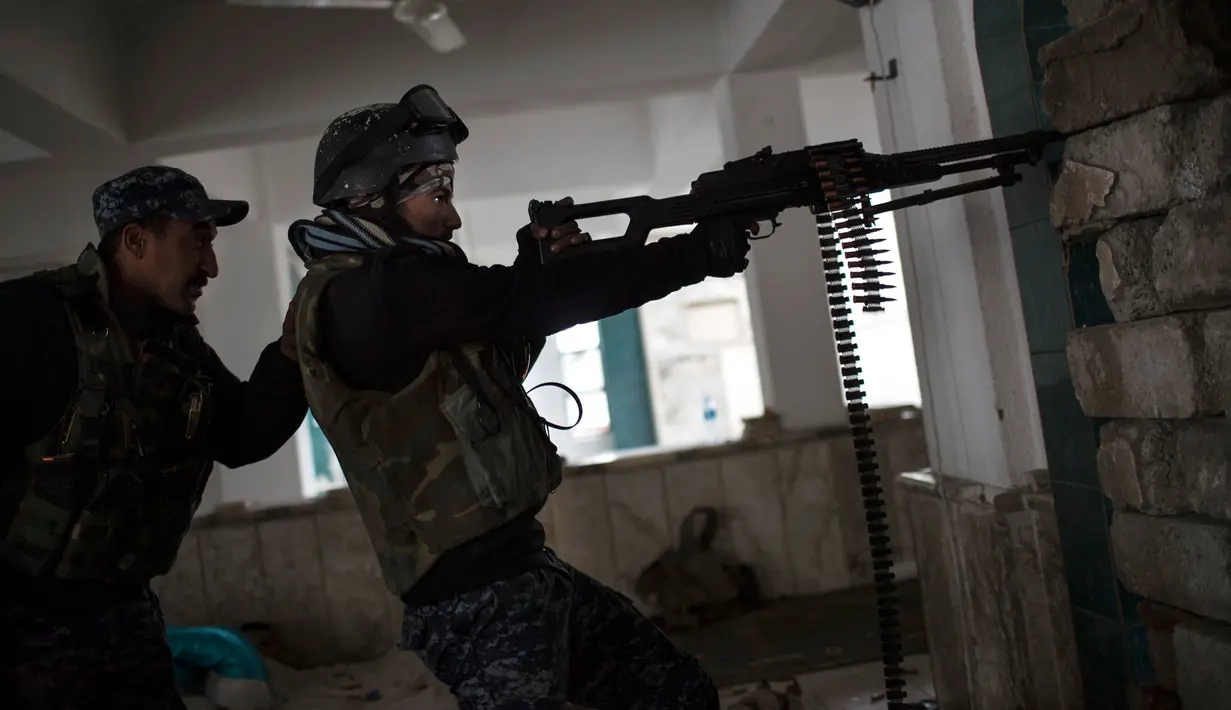 Dua polisi Irak memberikan tembakan kearah militan ISIS saat pertempuran di barat Mosul, Irak, 16 Maret 2017. (AP Photo/Felipe Dana)