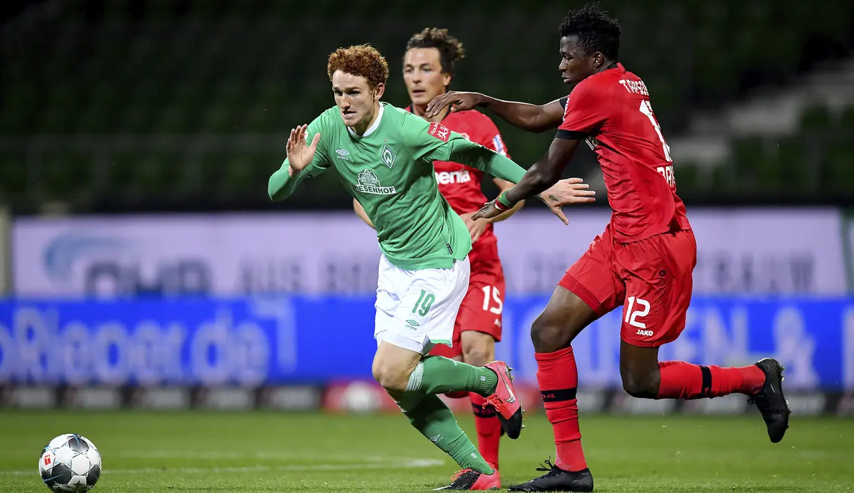 Pemain Bayer Leverkusen, Edmond Tapsoba, berebut bola dengan pemain Werder Bremen, Joshua Sargent, pada laga Bundesliga di Weserstadion, Bremen, Senin (18/5/2020). Bayer Leverkusen menang 4-1 atas Werder Bremen. (AP/Stuart Franklin)