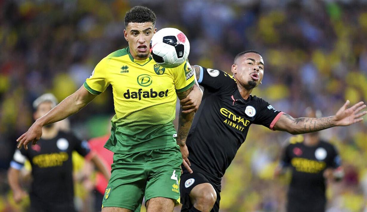 Pemain Norwich City, Ben Godfrey, berebut bola dengan striker Manchester City, Gabriel Jesus, pada laga Premier League di Stadion Carrow Road, Sabtu (14/9). Norwich City menang 3-2 atas Manchester City. (AP/Joe Giddens)