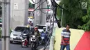 Pejalan kaki melintasi trotoar yang terhalang instalasi kabel di Jalan Kyai Maja, Jakarta, Rabu (10/4). Selain menganggu kenyamanan pejalan kaki, kondisi instalasi kabel yang semrawut tersebut juga berbahaya apabila mengandung aliran listrik. (Liputan6.com/Immanuel Antonius)