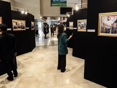 Pengunjung melihat karya foto dalam Pameran Foto Jurnalistik Warna-Warni Parlemen dengan tema Bangkit Lebih Cepat di loby Nusantara II DPR, Senayan, Jakarta, Senin (29/8/2022). Pameran ini sebagai bentuk apresiasi terhadap karya-karya  jurnalistik wartawan foto yang melaksanakan tugas di parlemen. (Liputan6.com/Johan Tallo)