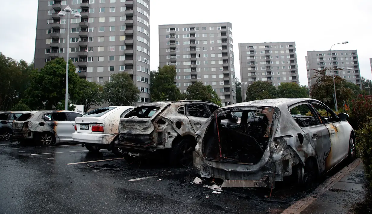 Deretan mobil yang terparkir di kota Gothenburg, Swedia hangus dan rusak, Selasa (14/8). Sekelompok orang bertopeng dan berpakaian hitam dilaporkan menjadi pelaku pembakaran puluhan mobil di sejumlah kota dalam semalam. (Adam Ihse/TT via AP)