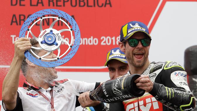 Pembalap LCR Honda, Cal Crutchlow menyemprotkan sampanye pada salah satu krunya saat merayakan kemenangannya pada balapan MotoGP Argentina di atas podium Sirkuit Termas de Rio Hondo, Minggu (8/4). (AP/Natacha Pisarenko)