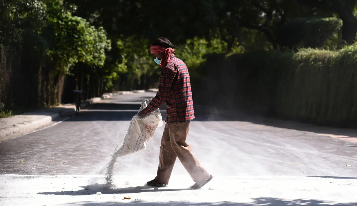 Pekerja menebarkan bubuk untuk menangkal penyebaran flu burung di Kebun Binatang Delhi di New Delhi, India, Rabu (19/10). Kebun binatang ditutup karena wabah flu burung yang menyerang hewan di kebun binatang tersebut. (AFP PHOTO / Sajjad Hussain)