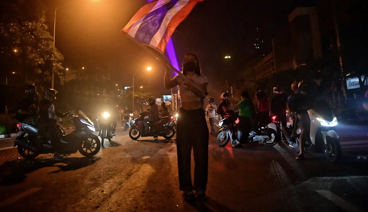 Seorang pengunjuk rasa mengibarkan bendera selama demonstrasi di Bangkok, Thailand, Minggu (6/9/2021). Aksi unjuk rasa yang menyuarakan pengunduran diri Perdana Menteri Thailand, Prayut Chan-O-Cha makin mencekam hingga malam hari. (AFP/Lillian Suwanrumpha)