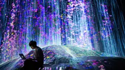 Anggota Teamlab Jepang bekerja menggunakan laptopnya di ruang instalasi digital air terjun di Mori Building Digital Museum Seni, Tokyo, Jepang (1/5). (AFP Photo/Behrouz Mehri)