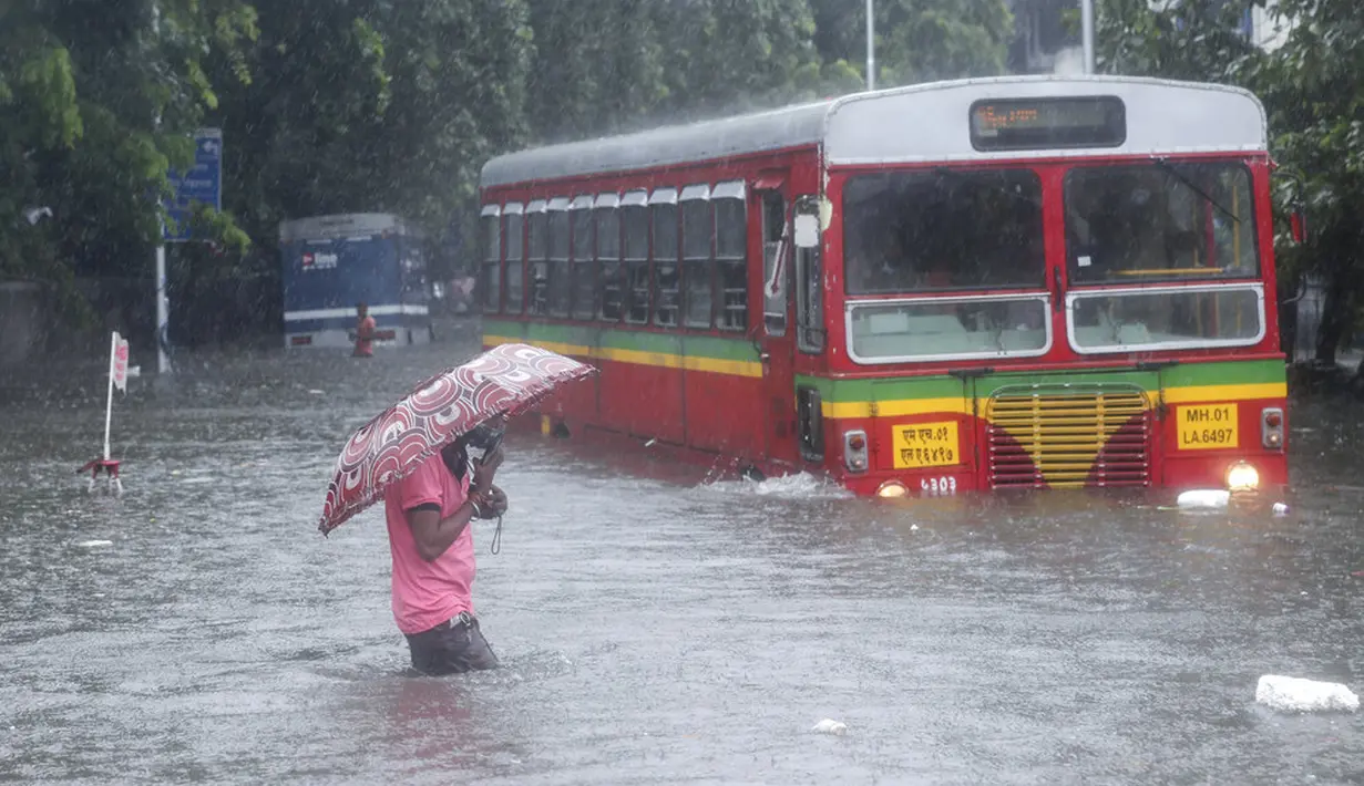 Seorang pria berjalan melintasi jalan yang banjir saat hujan lebat di Mumbai, India, Rabu (9/6/2021). Mumbai terendam banjir usai diguyur hujan lebat. (AP Photo/Rafiq Maqbool)