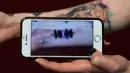 Hanna Washlake mendengarkan tato gelombang suara yang mengeluarkan pesan dari ibunya di Black Raven Tattoo California, 12 April 2018. Untuk mendengarkan Soundwave Tattoo yang perlu dilakukan memegang telepon kamera ke gambar tato. (AFP/FREDERIC J. BROWN)