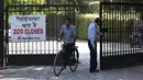 Pekerja masuk ke dalam Kebun Binatang Delhi yang tutup sementara di New Delhi, India, Rabu (19/10). Kebun binatang ditutup karena wabah flu burung yang menyerang hewan di kebun binatang tersebut. (AFP PHOTO / Sajjad Hussain)