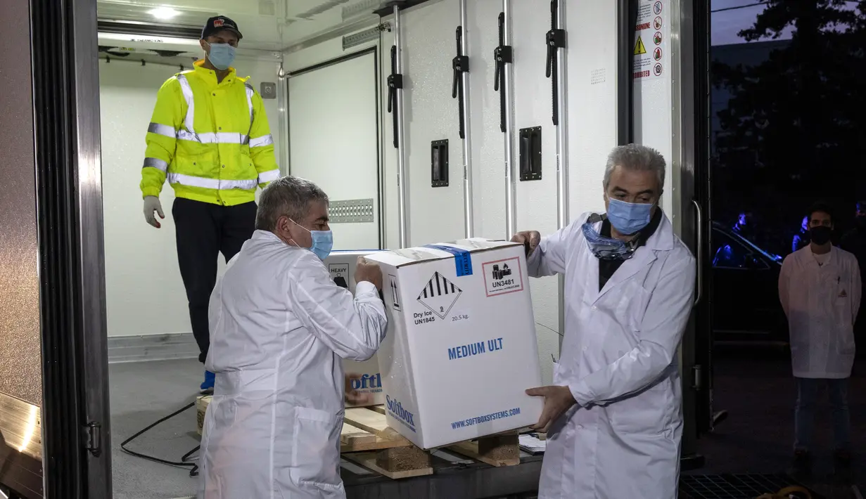 Dua petugas kesehatan mengeluarkan kotak berisi vaksin COVID-19 dari Pfizer saat tiba untuk pertama kalinya di Kryoneri village, dekat Athena, Yunani, Sabtu (26/12/2020). Gelombang pertama vaksin untuk melawan COVID-19 tiba di Yunani. (AP Photo/Yorgos Karahalis)