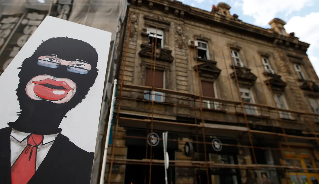 Sebuah gambar dibawa saat aksi mengkritik rencana tepi laut Belgrade di Beograd, Serbia, Selasa (25/4). Demo dilakukan satu tahun setelah pembongkaran misterius di daerah yang ditandai untuk proyek real estat yang didanai UEA. (AP Photo/Darko Vojinovic)