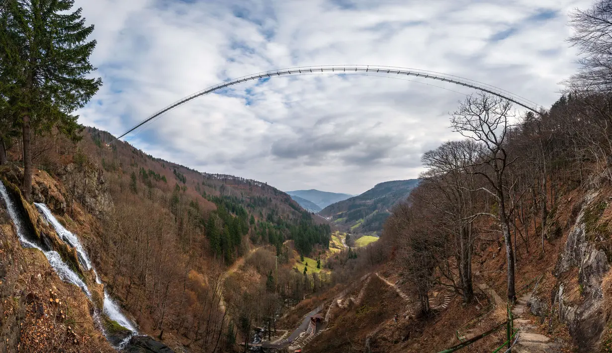 Panorama dari 27 foto yang diambil pada 3 Maret 2023 menunjukkan jembatan gantung yang sedang dibangun, menghadap ke air terjun di Todtnau, barat daya Jerman. Pembangunan jembatan sepanjang 450 meter yang digantung dengan ketinggian hingga 120 meter ini diharapkan selesai pada Mei 2023 dan menjadi daya tarik wisata utama di Black Forest. (PATRICK HERTZOG / AFP)