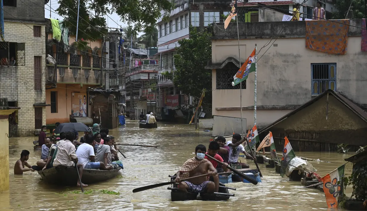 Warga menaiki perahu di atas jalan yang terendam banjir menyusul hujan lebat di Ghatal, distrik Paschim Medinipur, sekitar 100 km dari Kolkata (2/8/2021). Banjir parah akibat hujan lebat membuat jalanan di Ghatal berubah bak sungai. (AFP/Dibyangshu Sarkar)