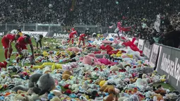 Suporter melempar mainan ke lapangan selama pertandingan Liga Turki (Super Lig) antara Besiktas dan Antalyaspor di stadion Vodafone di Istanbul, Minggu (26/2/2023). Ribuan mainan akan dikirim ke anak-anak di daerah yang terkena dampak gempa Tukri , banyak dari mereka mengungsi setelah rumah mereka dihancurkan. (AP Photo)