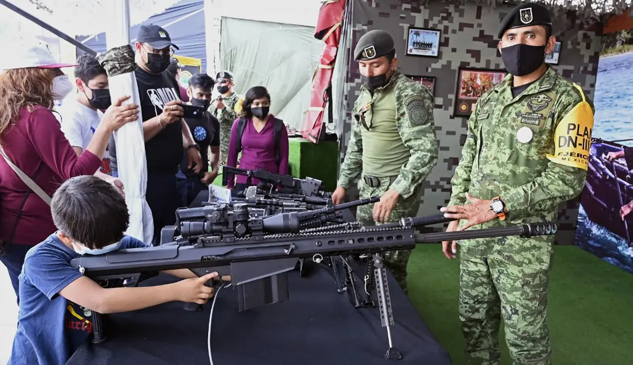 Seorang anak laki-laki mengarahkan senjata yang digunakan oleh Tentara Meksiko dalam pameran yang disebut The Great Force of Mexico di Alun-Alun Zocalo, Mexico City, Meksiko, 20 September 2021. (ALFREDO ESTRELLA/AFP)