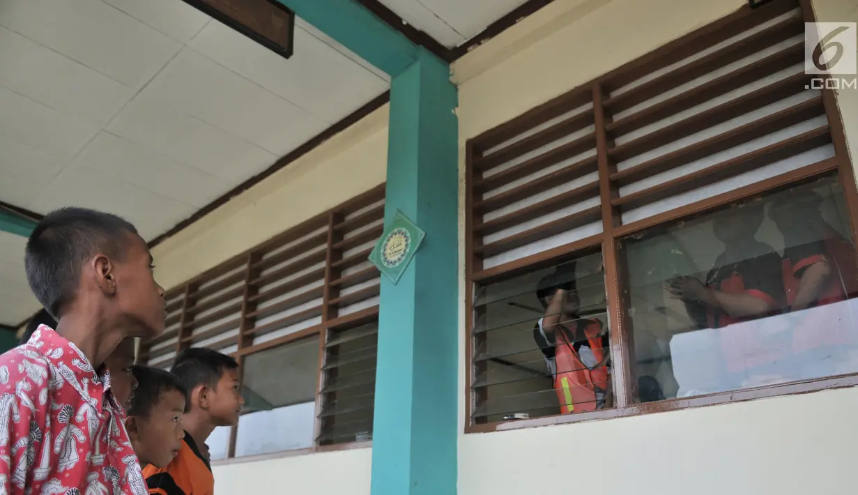 Sejumlah siswa SD melihat proses pemasangan kipas angin dan penyaring udara di SD Negeri Cilincing 07 Pagi, Jakarta, Kamis (19/9/2019). Pemasangan tersebut menjadi bagian dari instalasi Sekolah Aman Asap. (merdeka.com/Iqbal Nugroho)