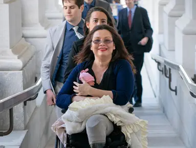 Senator negara bagian Illinois, Tammy Duckworth membawa bayinya ke ruangan kongres Gedung Capitol Hill, Washington DC, AS, Kamis (19/4). Duckworth (50) menggendong sang putri dalam pengambilan suara untuk nominasi pengurus NASA. (AP/J. Scott Applewhite)