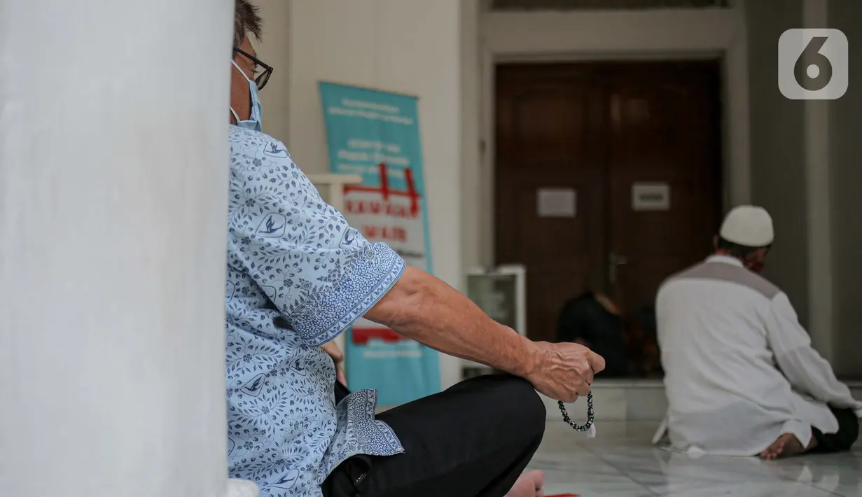 Sejumlah warga melaksanakan salat zuhur di halaman depan Masjid Cut Meutia, Jakarta, Jumat (18/9/2020). Pemprov DKI Jakarta kembali meniadakan kegiatan ibadah salat Jumat dan salat lima waktu berjemaah di semua Masjid Raya selama PSBB. (Liputan6.com/Faizal Fanani)
