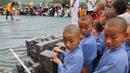 Biksu muda Shaolin berdiri di samping kunci batu saat menyaksikan kompetisi seni bela diri '72 Arts of Shaolin' di kuil Shaolin, Provinsi Henan, China, 30 Juli 2017. Kompetisi ini menampilkan para jago kungfu yang memamerkan kekuatan fisik. (STR AFP)