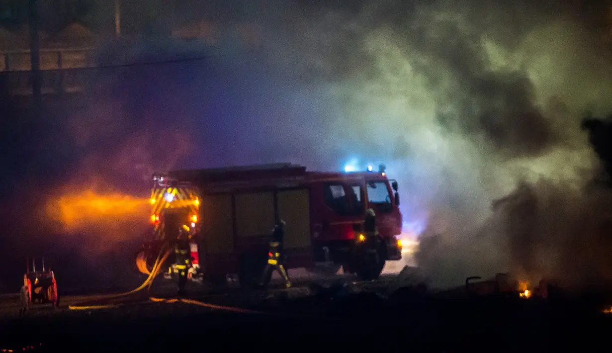 Petugas pemadam kebakaran tiba di lokasi kamp penampungan imigran di Dunkirk, Prancis, Senin (10/4).  Kamp yang menampung sekitar 1500 orang ini hangus terbakar api. (AFP PHOTO / PHILIPPE HUGUEN)