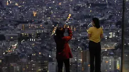 Pengunjung berfoto dari dek observasi Shibuya Sky di Tokyo, Sabtu (9/10/2021). seminggu setelah Jepang sepenuhnya keluar dari keadaan darurat virus corona untuk pertama kalinya dalam lebih dari enam bulan. (AP Photo / Kiichiro Sato)