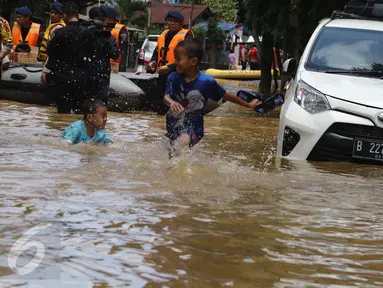 Dua orang anak bermain dekat mobil yang terendam banjir di permukiman Bukit Duri, Jakarta, Kamis (16/2). Meluapnya Bendungan Katulampa, Bogor, menyebabkan kawasan Bukit Duri tergenang air dengan ketinggian 10 - 80 cm. (Liputan6.com/Helmi Afandi)