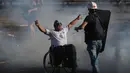 Pengunjuk rasa difabilitas meminta bantuan saat polisi menembakkan gas air mata untuk membubarkan protes di Santiago, Chile, Jumat (27/12/2019). Protes Chile berubah menjadi gerakan yang jauh lebih besar dan luas dengan daftar panjang tuntutan. (AP Photo/Fernando Llano)
