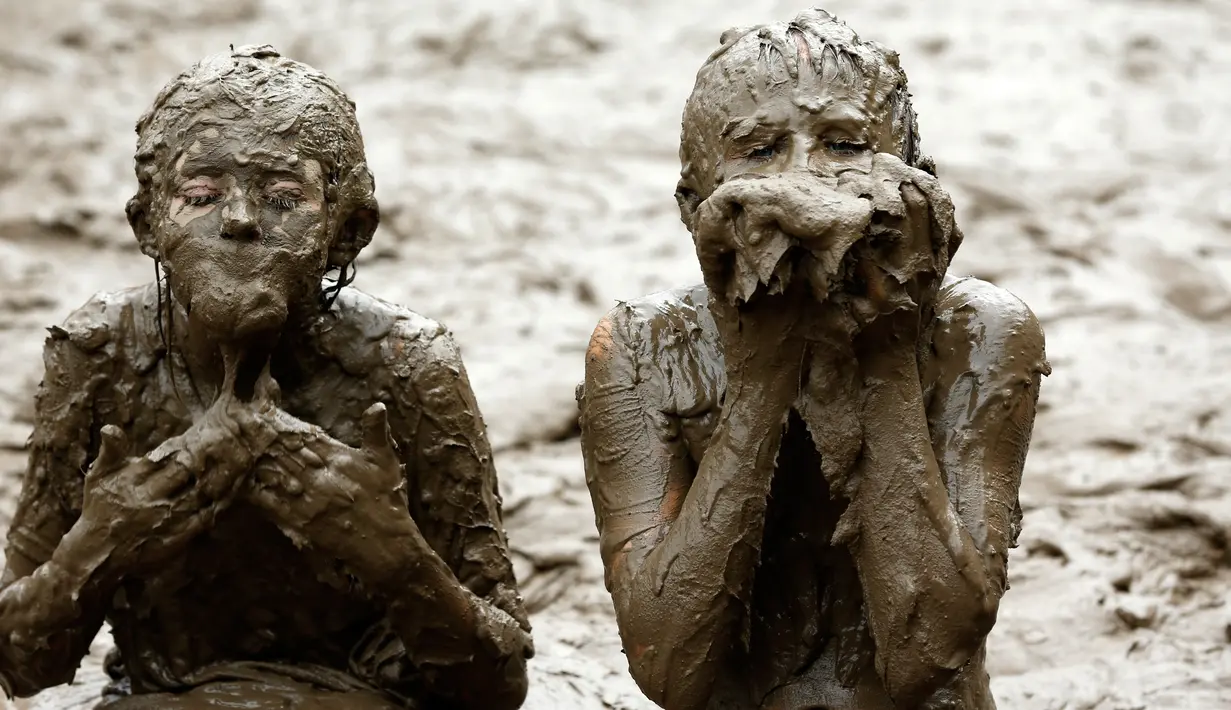 Dua orang anak bermian lumpur saat perayaan Mud Day di Nankin Mills Park di Westland, Michigan, AS (11/7). (AFP Photo/Jeff Kowalsky)