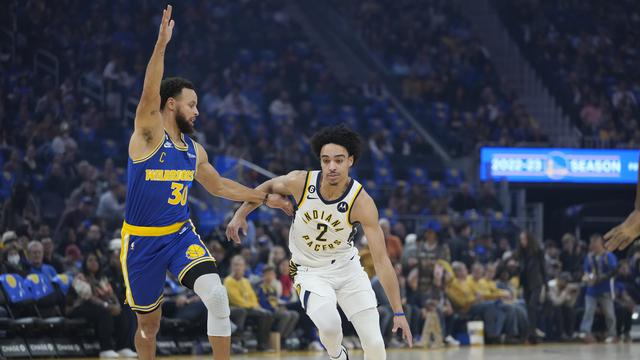 Rookie Indiana Pacers, Andrew Nembhard melewati penjagaan pemain Warriors Stephen Curry di lanjutan NBA 2022/2023