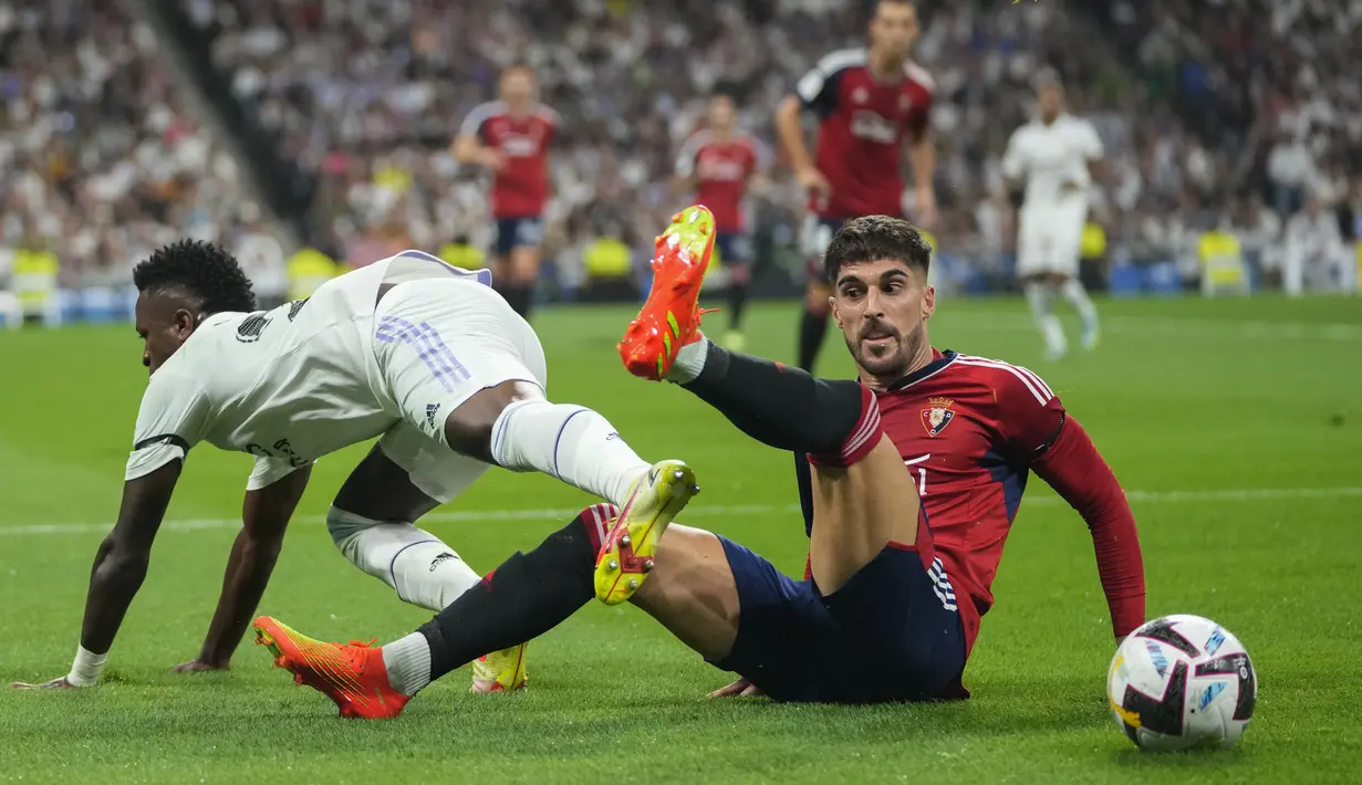 Bek Osasuna Nacho Vidal berebut bola dengan penyerang Real Madrid Vinicius Junior pada pekan ketujuh Liga Spanyol 2022/2023 di Stadion Santiago Bernabeu, Senin dini hari WIB (3/10/2022). Dengan hasil ini, Real Madrid memang masih menjaga rekor tak terkalahkan, tapi mereka gagal menyalip Barcelona. (AP Photo/Manu Fernandez)