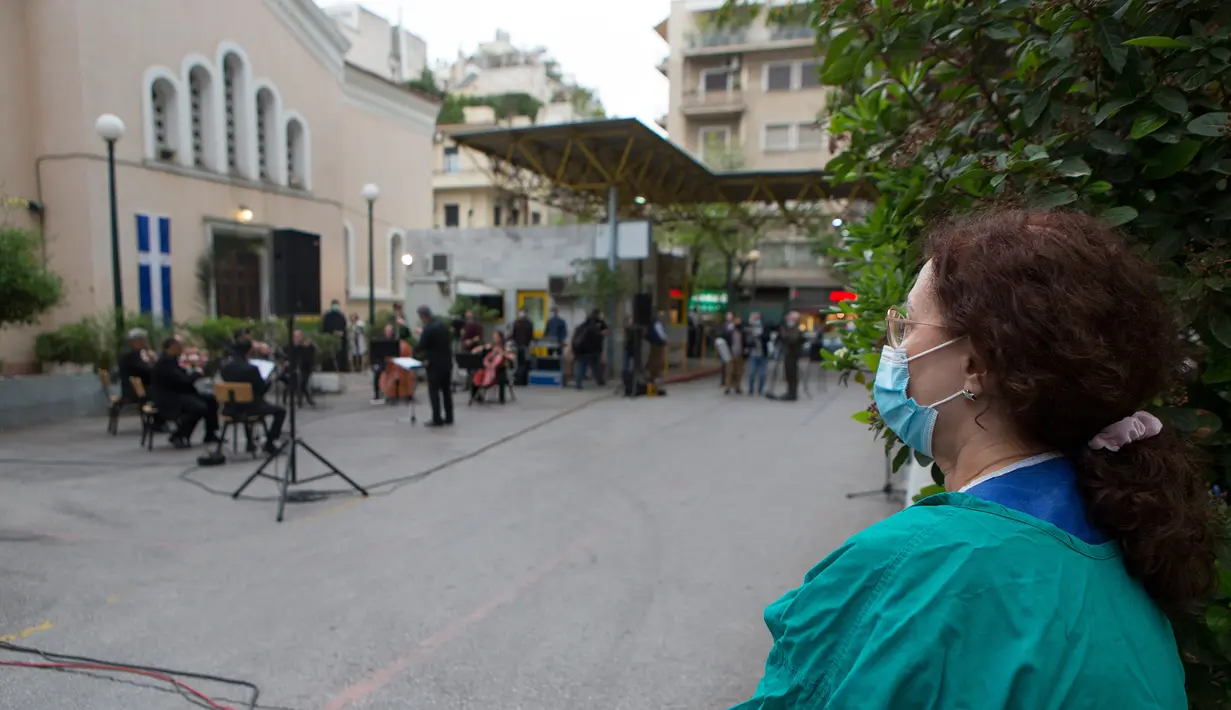 Seorang tenaga medis dari Rumah Sakit Umum Evaggelismos menonton konser ERT (Hellenic Broadcasting Corporation) Modern Music Orchestra di Athena, Yunani (20/4/2020). Konser digelar oleh ERT Modern Music Orchestra untuk menghormati staf medis dalam perjuangan melawan COVID-19. (Xinhua/Marios Lolos)