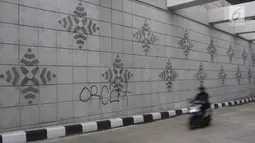 Pengendara motor melintasi coretan di dinding underpass atau lintas bawah Matraman, Jakarta Selatan, Rabu (2/5). Underpass yang belum genap sebulan diresmikan untuk diuji coba tersebut dihiasi coretan tangan jahil. (Liputan6.com/Arya Manggala)