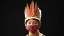 Elano de Souza (6) dari kelompok etnis pribumi Sateré Mawé mengenakan pakaian tradisional sukunya dan masker saat pandemi virus corona COVID-19 di daerah Gaviao, dekat Manaus, Brasil, Jumat (29/5/2020). (AP Photo/Felipe Dana)