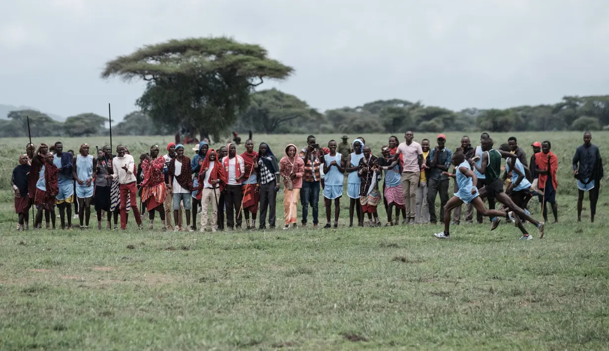 Orang Maasai melihat para pelari mengikuti kompetisi Olimpiade Maasai 2018 Kimana, Kenya (15/12). Olimpiade ini inisiatif dari kelompok konservasi internasional yang dipimpin oleh Born Free. (AFP Photo/Yasuyoshi Chiba)