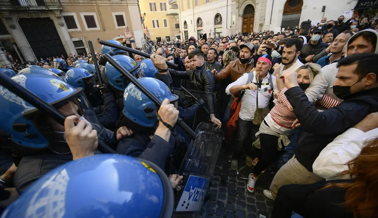 Polisi anti huru-hara (kiri) menggunakan tongkat untuk melawan pengunjuk rasa saat bentrokan dalam aksi protes oleh pemilik restoran dan aktivitas bisnis lainnya di luar parlemen di Piazza Montecitorio di Roma, Selasa (6/4/202). Mereka menuntut untuk membuka kembali bisnis. (Filippo MONTEFORTE/AFP)