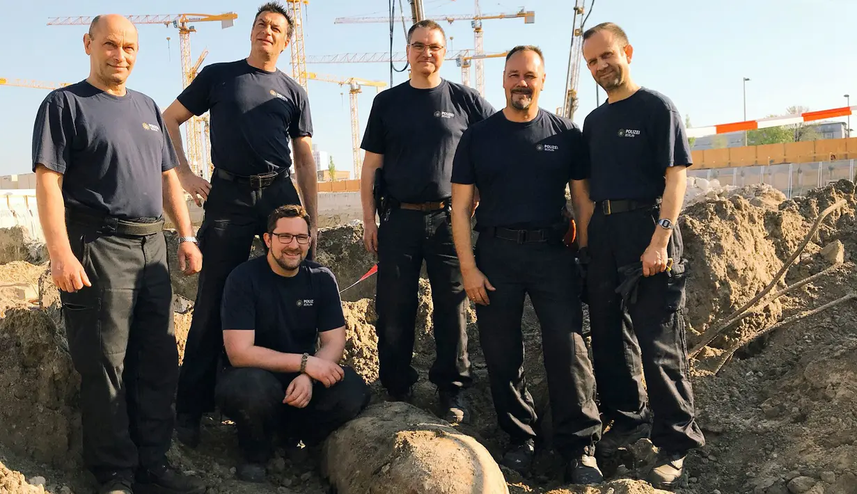 Tim penjinak bom berpose dengan bom perang dunia II saat ditemukan di Berlin, Jerman, Jumat (20/4). Bom yang ditemukan oleh pekerja konstruksi tersebut masih dalam kondisi aktif. (Polizei Berlin via AP)