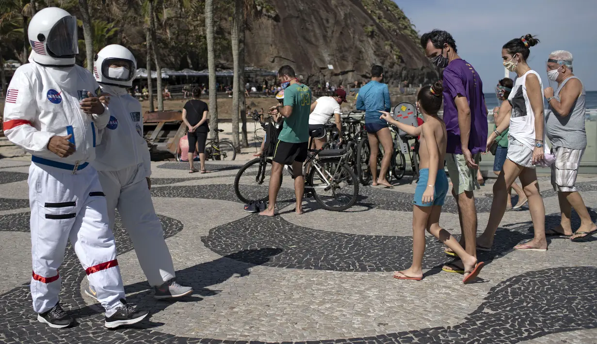 Akuntan Brasil Tercio Galdino (66) dan istrinya Alicea Galdino mengenakan pakaian pelindung mirip astronaut saat berjalan di sepanjang Pantai Leme, Rio de Janeiro, Brasil, 12 Juli 2020. (Mauro Pimentel/AFP)