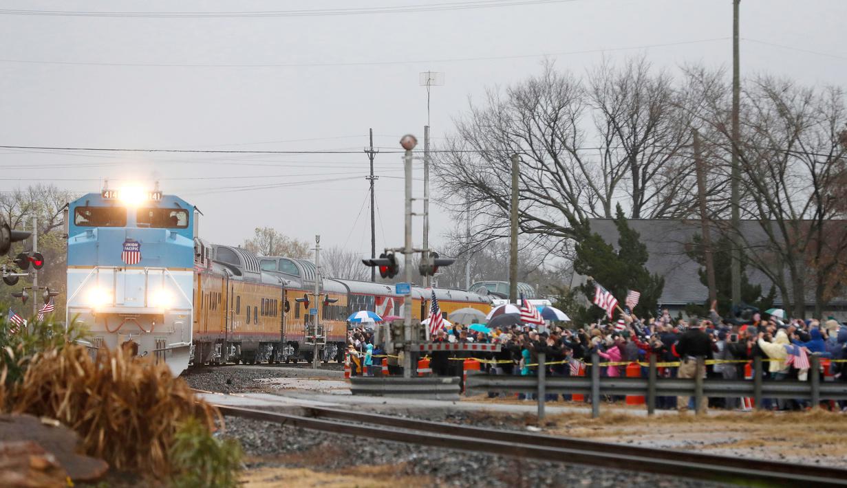Warga memberi penghormatan saat kereta pembawa peti jenazah Presiden ke-41 AS George HW Bush di Navasota, Texas, Kamis (6/12). Jenazah mantan presiden AS George HW Bush dibawa menggunakan kereta pemakaman khusus. (AP Photo/Gerald Herbert)