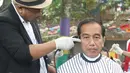 Presiden Joko Widodo saat mengikuti acara cukur rambut massal di Garut, Jawa Barat, Sabtu (19/1). Tak hanya Jokowi, Menteri PUPR Basuki Hadimuljono serta Kepala Sekretariat Presiden Heru Budi Hartono  ikut memangkas rambutnya. (Liputan6.com/Angga Yuniar)