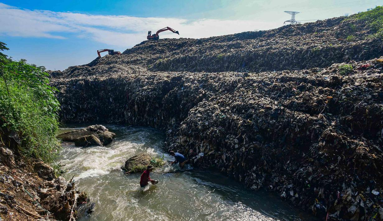 Warga memanfaatkan aliran Kali Pesanggrahan yang menyempit untuk mendulang benda-benda logam di kawasan Pasir Putih, Depok, Jawa Barat, Senin (27/4/2026), setelah longsoran sampah dari Tempat Pembuangan Akhir (TPA) Cipayung menutup sebagian badan sungai. (merdeka.com/Arie Basuki)