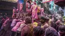 Umat Hindu berlumuran warna mendorong mobil yang membawa patung dewa Krishna selama festival Holi di Kolkata, India, Minggu, 5 Maret 2023. Dalam festival Holi di India, warga saling melempar serbuk warna-warni.(AP Photo/Bikas Das)