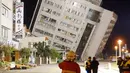 Petugas penyelamat memblokir area di dekat bangunan yang miring karena pondasinya ambruk usai terjadi gempa di Hualien, Taiwan (7/2). (AFP Photo/Paul Yang)