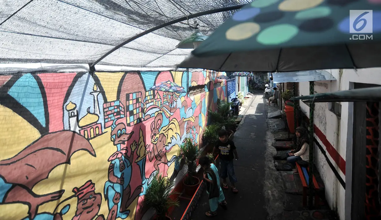 Anak-anak bermain di depan mural yang menghiasi gang di RT 13 RW 06, Jembatan Lima, Jakarta, Kamis (10/1). Pembuatan mural itu dimaksudkan agar lingkungan menjadi lebih tertata dan indah. (Merdeka.com/Iqbal Nugroho)