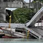 Sebuah kapal nelayan tertimpa jembatan beton yang ambruk di pelabuhan ikan Nanfangao di kota Suao (1/10/2019). Kejadian tersebut membuat setidaknya 14 orang terluka. (AFP Photo/Sam Yeh)