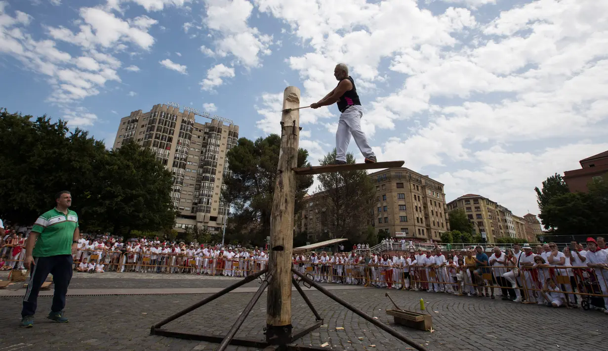 Patxi Larretxea memotong batang pohon menggunakan kapak pada hari ketiga festival San Fermin di Pamplona, Spanyol, Senin (8/7/2019). Festival San Fermin menghadirkan beberapa olahraga pedesaan Basque seperti menggergaji dan memotong pohon dengan kapak. (JAIME REINA/AFP)