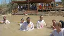 Umat Kristen mengikuti prosesi pembaptisan di Sungai Yordan, Jericho, Palestina, Jumat (13/9/2019). Situs Qasr al-Yahud sudah dinyatakan bebas ranjau darat sehingga bagi Anda yang ingin dibaptis seperti Yesus dahulu bisa melakukannya di sini. (HAZEM BADER/AFP)