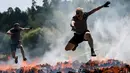 Dua pria menyeberangi rintangan api saat mereka mengikuti kompetisi Tough Viking di Stockholm, Swedia (12/5). Dalam lomba ini peserta harus menempuh jarak 8 km dengan 26 rintangan berat. (AFP/Jonathan Nackstrand)