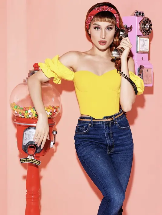 <p>Rambut cokelat berponi dengan bandana syal merah dipadukan outfit atasan kuning off shoulder dan celana denim, Cinta tampil bak Barbie bergaya retro. @claurakiehl</p>