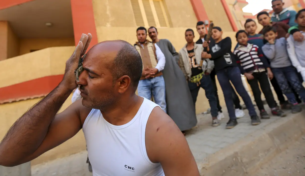 Karim Hussein memasukkan pecahan kaca ke dalam matanya saat unjuk kebolehan di Kairo (18/3/2016). Warga sekitar tampak menonton aksi mengerikan dari Karim Hussein "The Pharaoh"  (Reuters/ Mohamed Abd El Ghany)